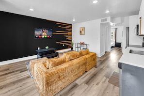 Una sala de estar moderna con una pared de acento negra, un televisor de pantalla plana y un sofá de madera.