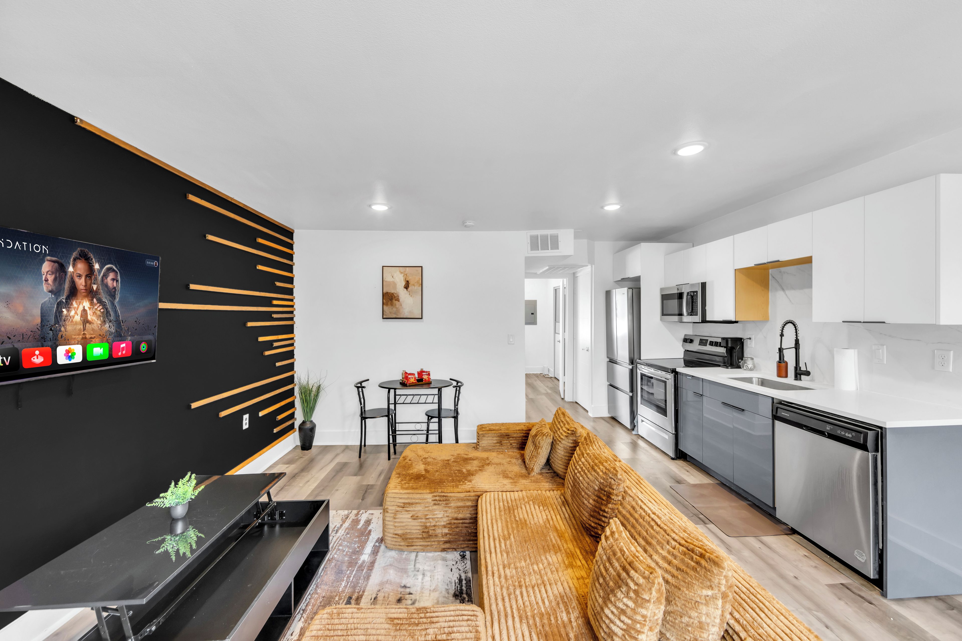 Un salon moderne avec un mur d’accent noir, un téléviseur à écran plat, un canapé et une table basse.