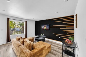 Modern lounge with plush sectional, accent wall, and TV - Comfy 1BR l Sleeps 4 l Near DT w/ Free Parking (Dallas)