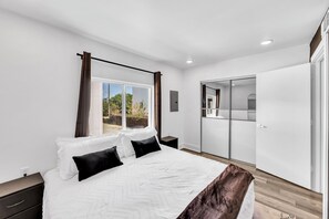 A bedroom with a bed, a nightstand, a wardrobe, and a sliding door to a balcony. - Comfy 1BR l Sleeps 4 l Near DT w/ Free Parking (Dallas)