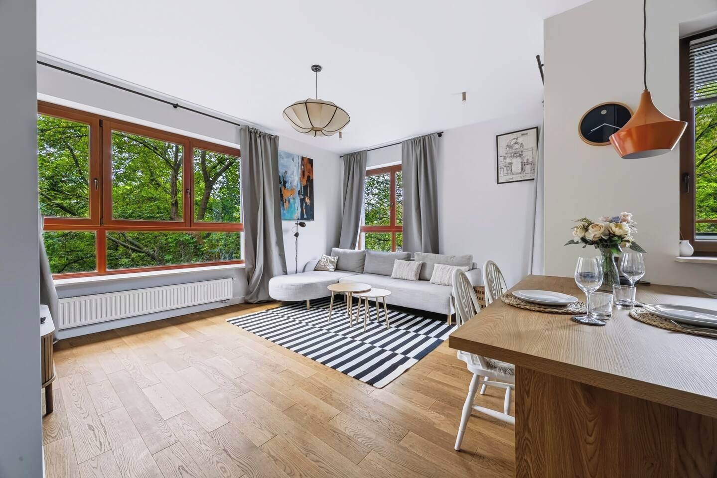 A modern living room with a sofa, dining table, and large windows.