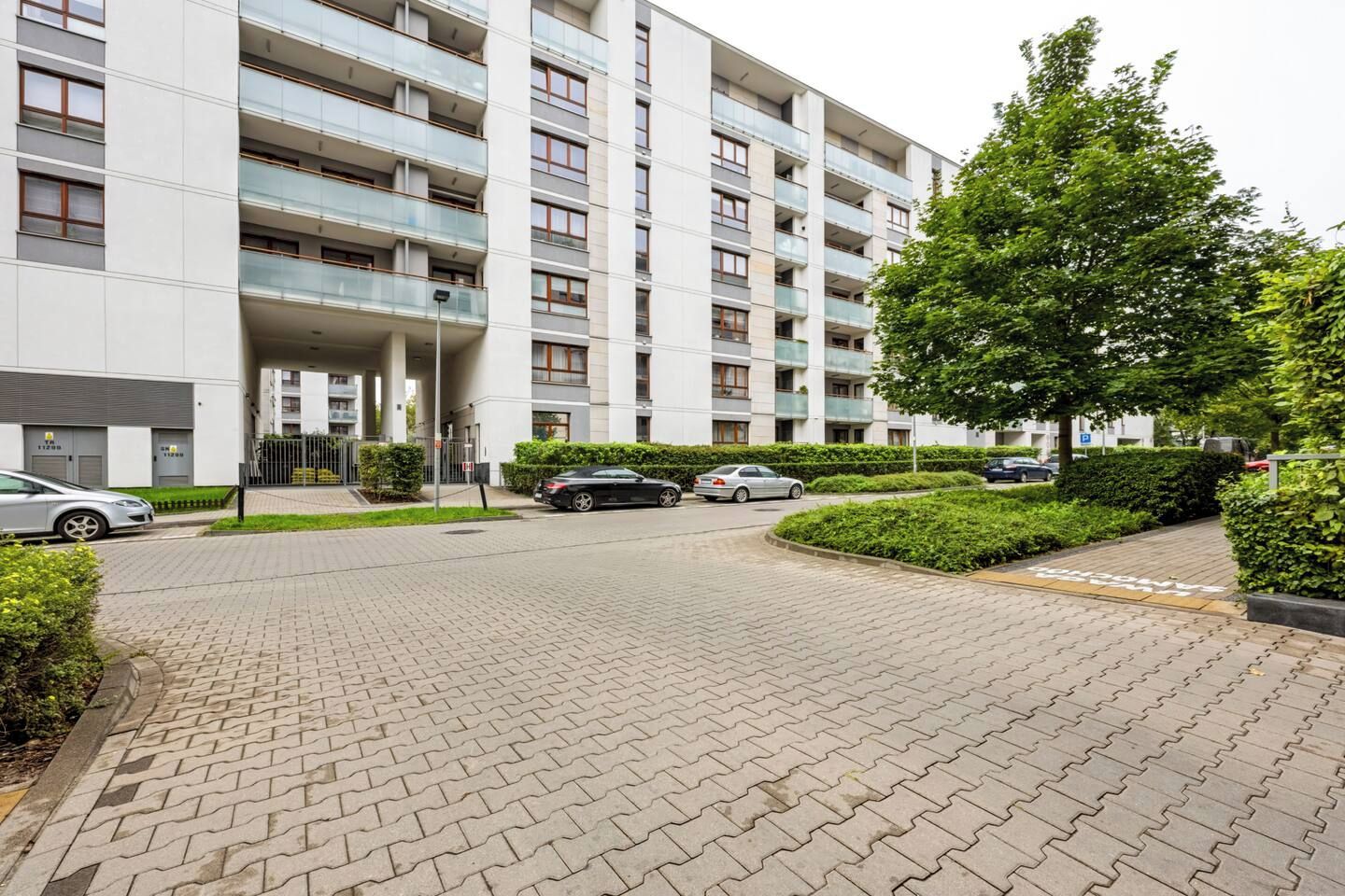 Ein mehrstöckiges Wohngebäude mit befestigter Auffahrt und geparkten Autos.