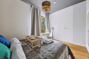 A bedroom with a bed, a bedside table with cups, a chair, and a wardrobe. - Warsaw Green Żoliborz Apt — Parking & Balcony (Warszawa)