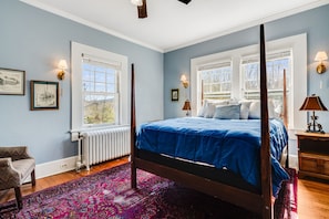 Une chambre à coucher avec un lit à baldaquin, un radiateur, une chaise et une fenêtre donnant sur un beau paysage.