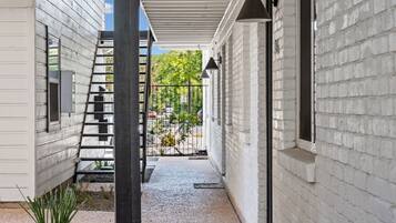 A covered outdoor area with a gravel path, a metal ladder, and a brick wall.