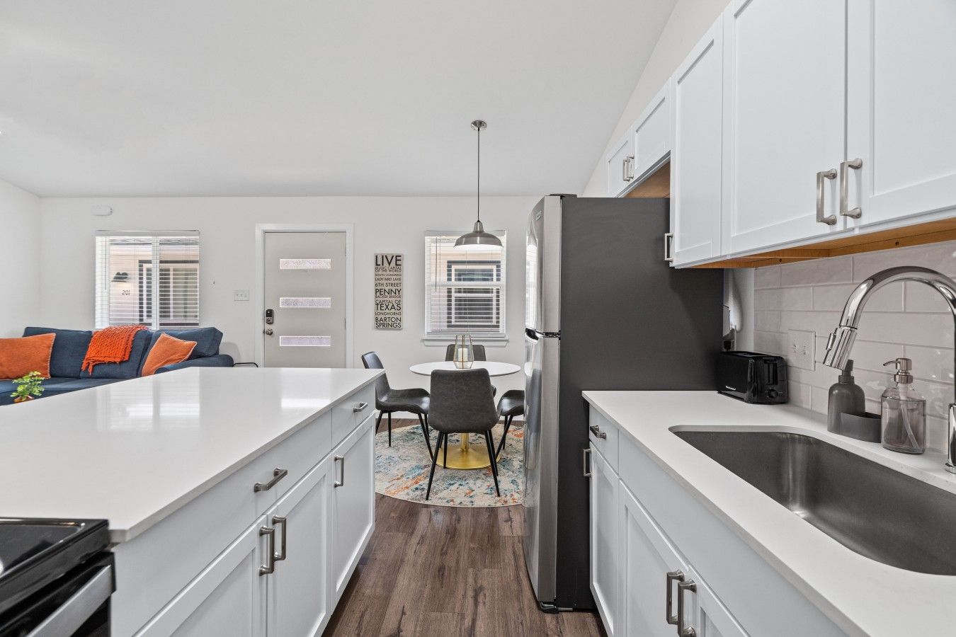 A modern kitchen with white cabinetry, a central island, and a built-in sink.
