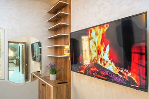 A modern living room with a fireplace, a mounted TV, and a wooden shelving unit.