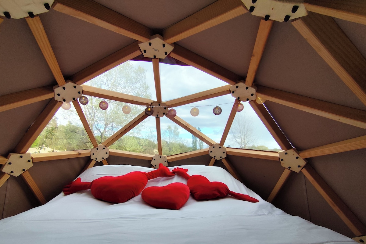 Quarto com teto inclinado, vigas de madeira e cama com almofadas vermelhas.