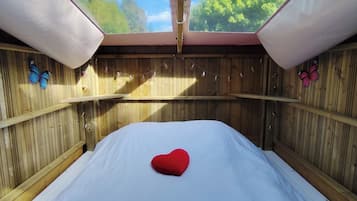 Une chambre avec un lit, des murs en bois et une vue sur les arbres.