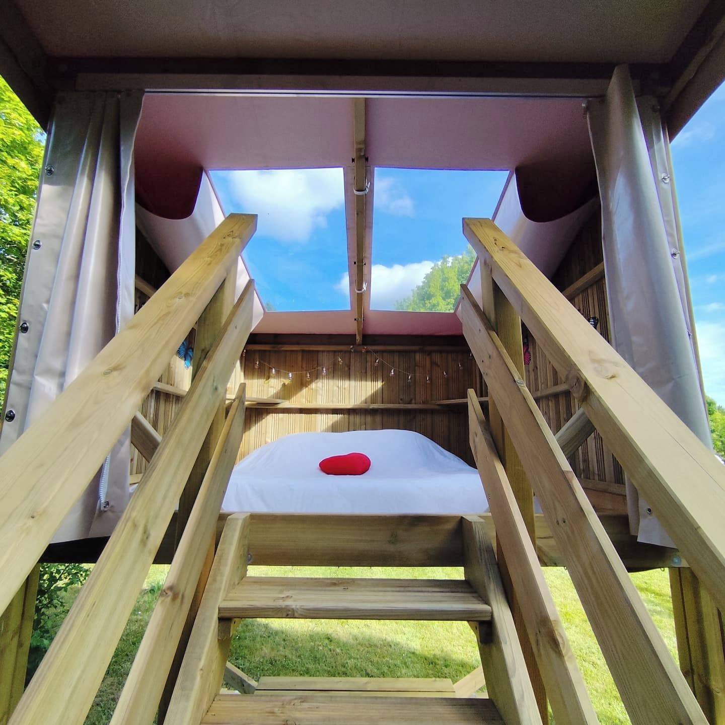 A wooden deck with a skylight, a red cushion, and a view of the sky.