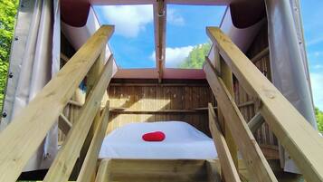 A wooden deck with a skylight, a red cushion, and a view of the sky.