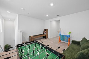 A room with a foosball table, a dartboard, and a small basketball hoop. - Sleeps~12, 8-Beds 3-Baths, Backyard, Gameroom, Prime Location (Lincoln)
