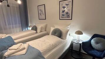Ein Hotelzimmer mit zwei Betten, einem kleinen Tisch, einem Stuhl und Bildern an den Wänden.