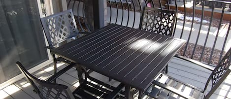 A balcony with a metal table and chairs, a glass door, and a view of the outdoors.