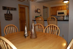A dining area with a wooden table and chairs, a kitchen in the background, and a wall-mounted telephone. - Marvelous 2-bedroom condo in Crested Butte for your getaway (Crested Butte)