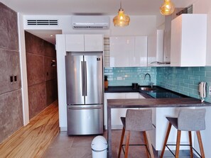 Une cuisine moderne équipée d’un réfrigérateur en acier inoxydable, d’un évier et de tabourets de bar.
