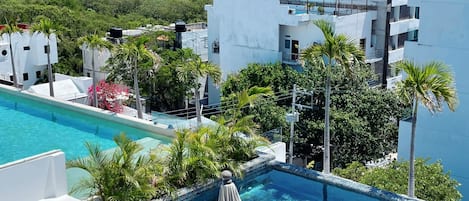 A rooftop swimming pool with a view of the ocean and surrounding buildings.