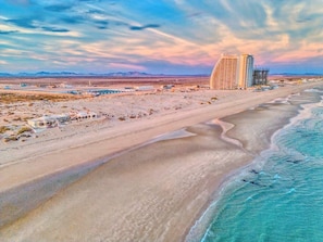 A coastal area with a beach, a hotel, and a construction site.