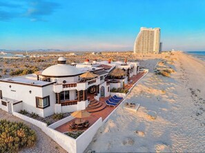 A beachfront hotel with a pool, sun loungers, and a view of the ocean.