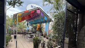 An outdoor patio area with tables and chairs, potted plants, and a colorful canopy. - Luz de Luna (Oaxaca)