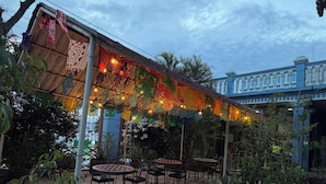 An outdoor patio with tables and chairs, surrounded by potted plants and decorated with colorful paper lanterns. - Luz de Luna (Oaxaca)
