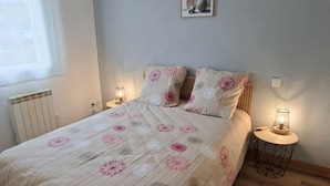 Une chambre à coucher avec un lit, des lampes de chevet, un radiateur et un tableau au mur.