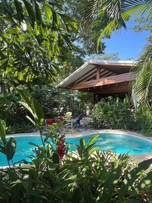 Un espace piscine doté d’un coin salon abrité et d’une végétation luxuriante.