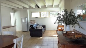 A spacious kitchen with a refrigerator, a washing machine, and a dining area with a wooden table and chairs.