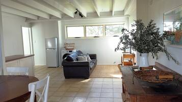 A spacious kitchen with a refrigerator, a washing machine, and a dining area with a wooden table and chairs.