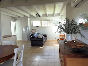 A spacious kitchen with a refrigerator, a washing machine, and a dining area with a wooden table and chairs.