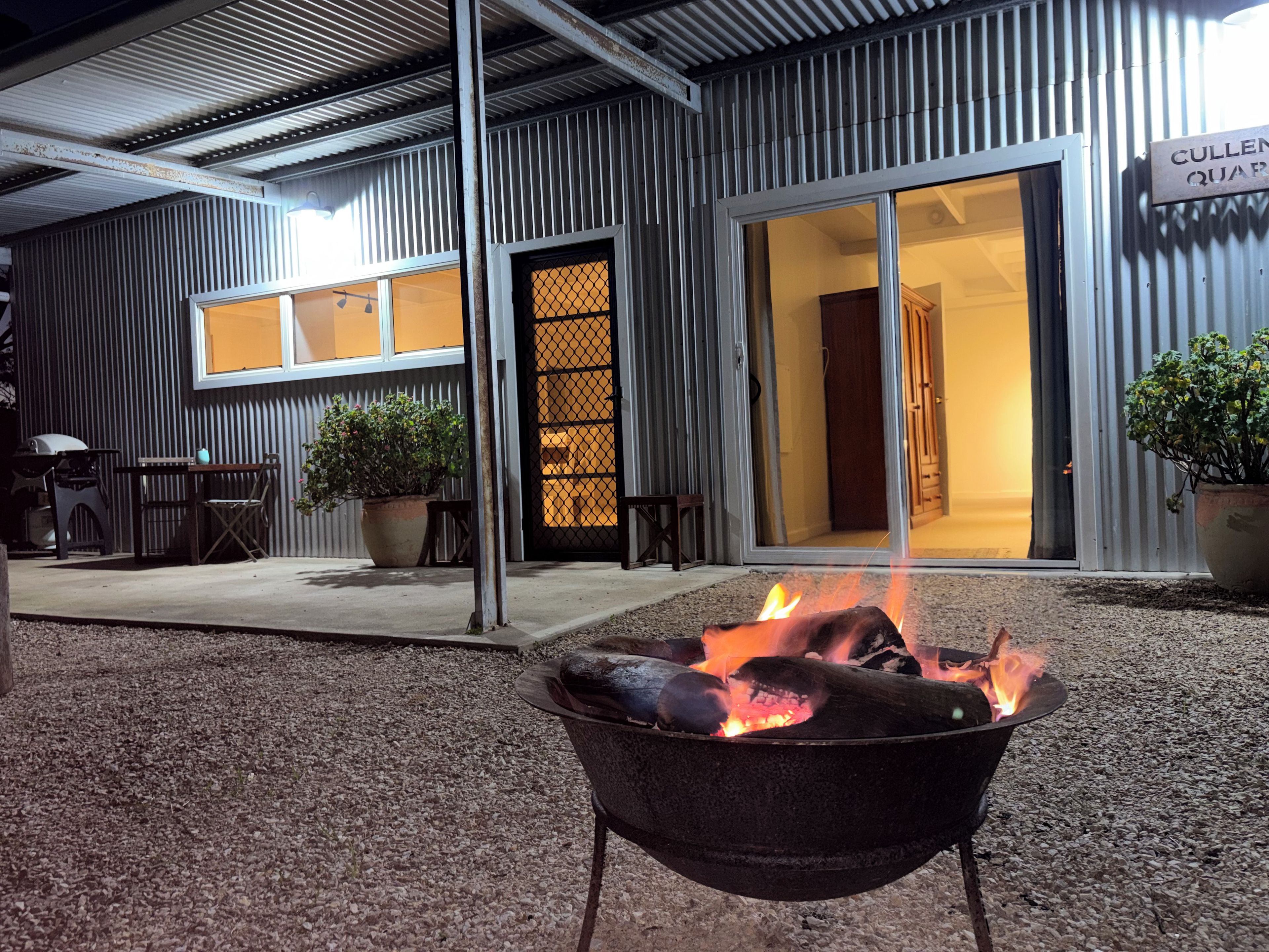 Un espace extérieur aménagé avec un foyer, un barbecue et des plantes en pot.