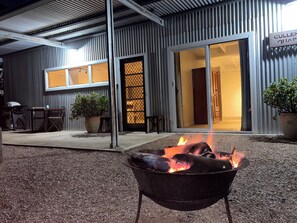 An outdoor seating area with a fire pit, a grill, and potted plants.