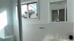 A bathroom with a toilet, a sink, and a window.