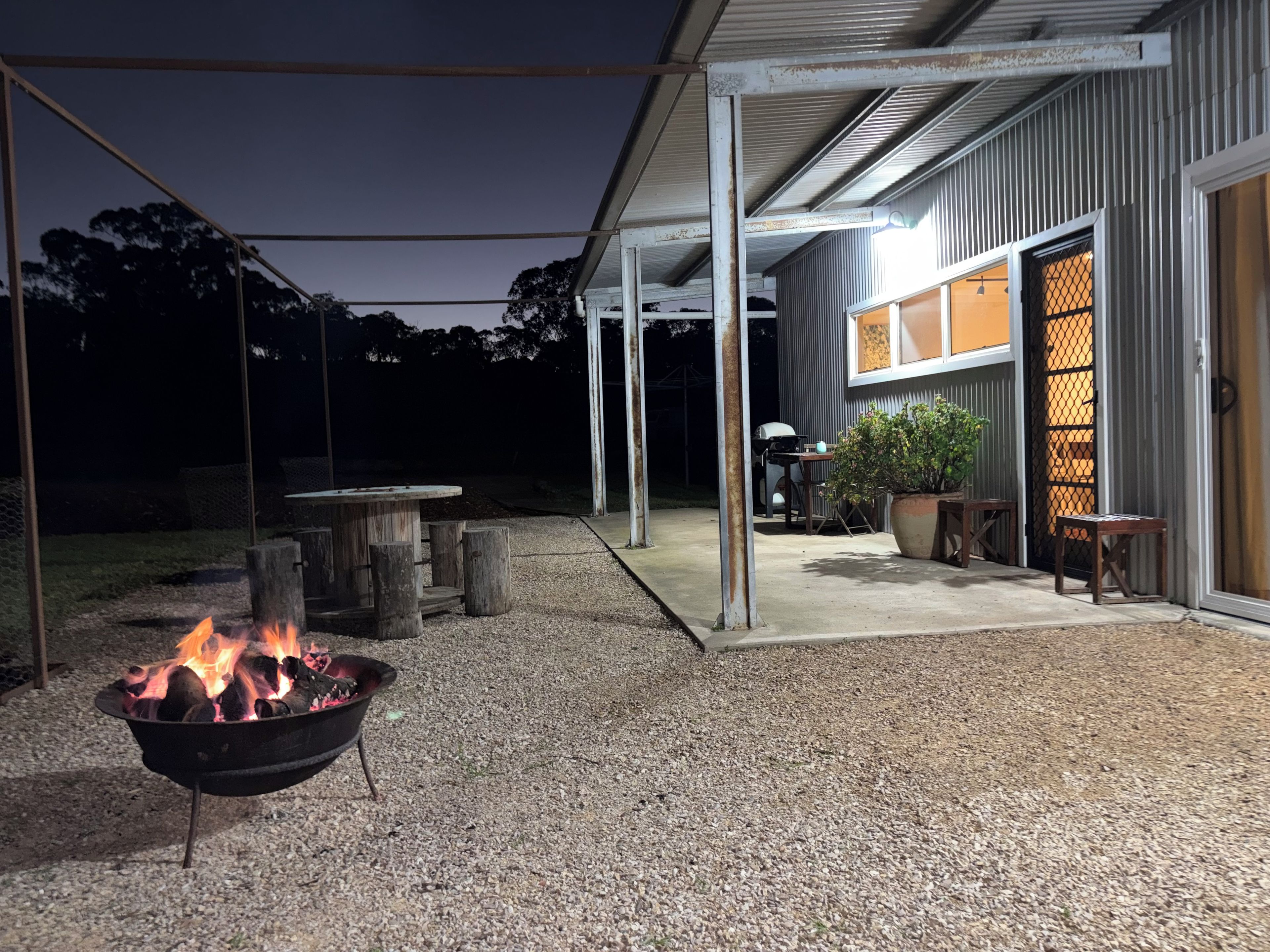 An outdoor patio area with a fire pit, a covered seating area, and a building entrance.
