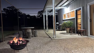 An outdoor patio area with a fire pit, a covered seating area, and a building entrance.