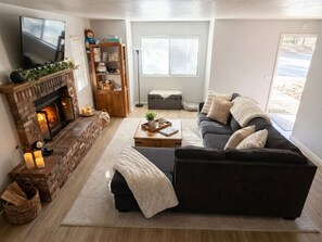 Ein Wohnzimmer mit Kamin, einer Couch, einem Fernseher und einem Bücherregal.
