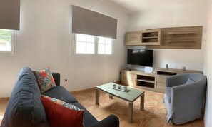 Ein Wohnzimmer mit einer Couch, einem Couchtisch, einem Fernseher und einem Sessel.