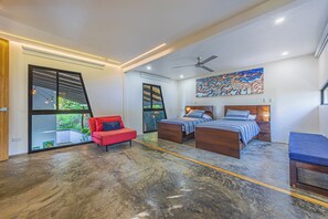 A modern bedroom with a large window, a red chair, two beds, and a ceiling fan. - Casa Mable, Pool w/ Whale's Tail & Ocean View (Uvita)