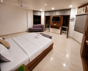 Un dormitorio moderno con una cama grande, una zona de estar y un balcón con vistas.