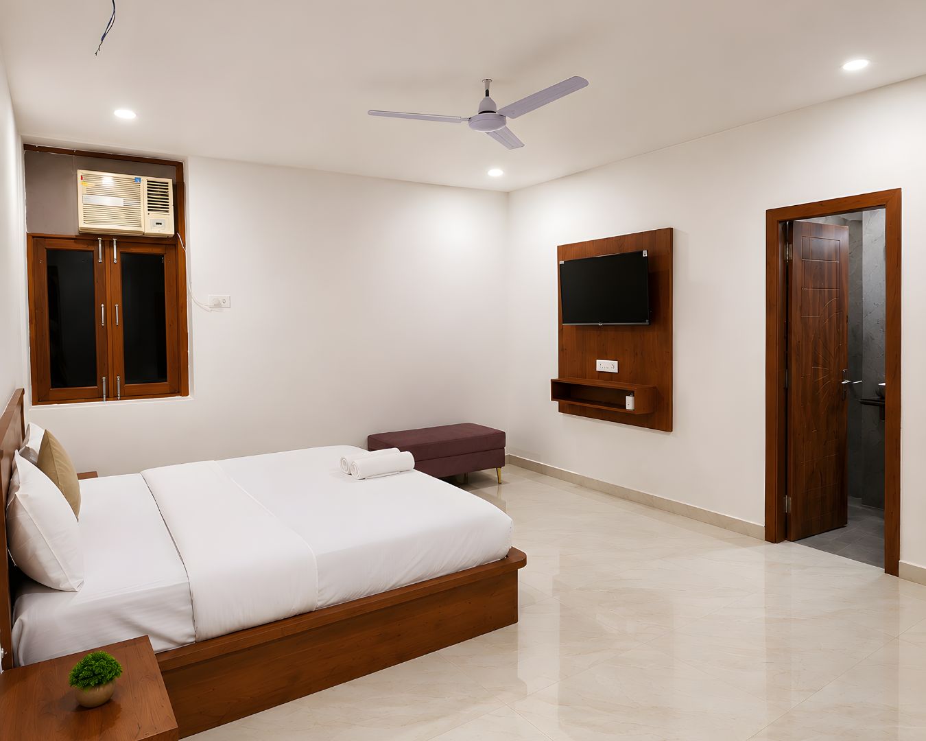A bedroom with a bed, a ceiling fan, a mounted TV, and a wardrobe.