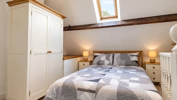A bedroom with a bed, bedside tables, a wardrobe, a skylight, and a sloped ceiling.