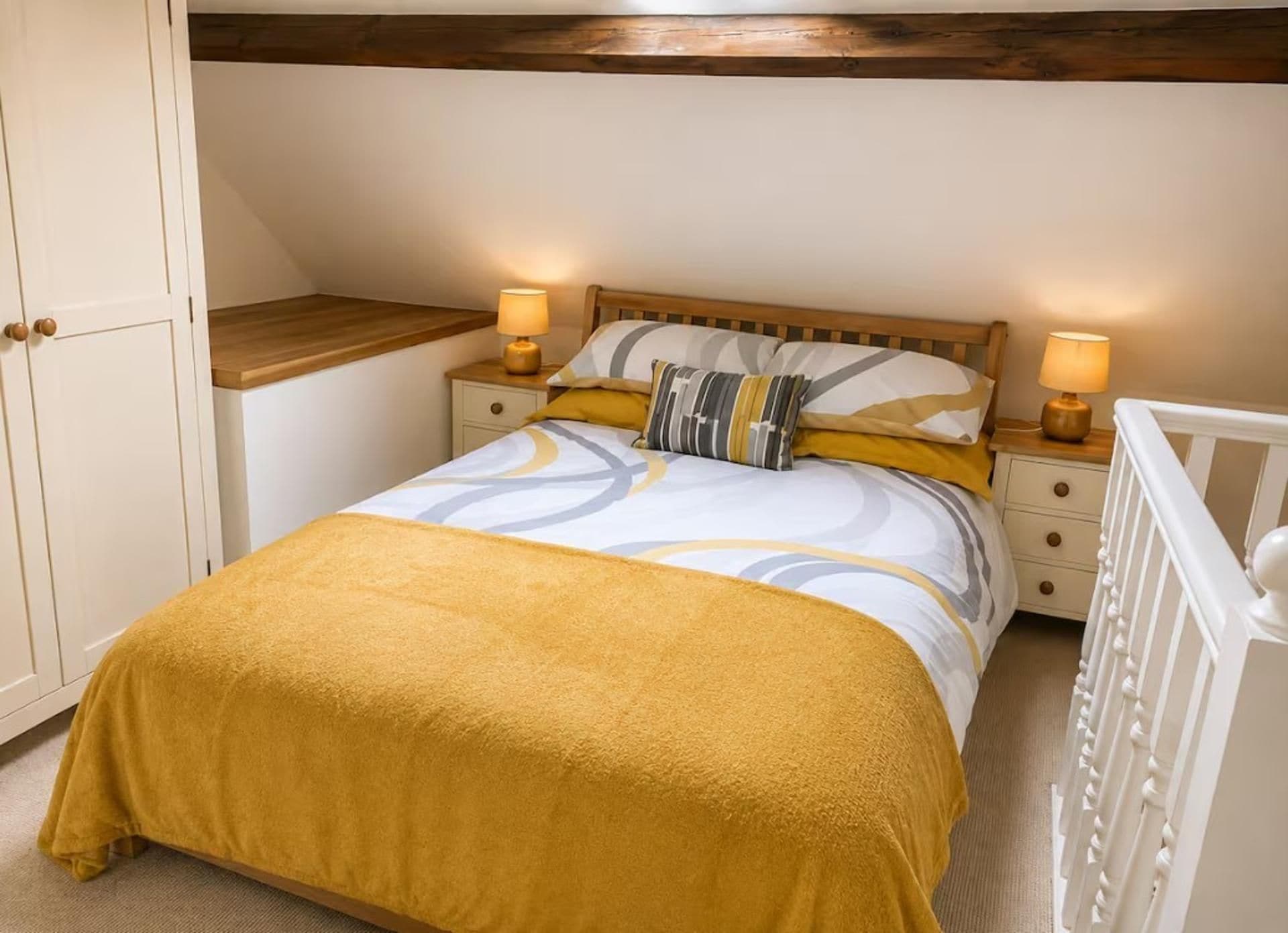Une chambre à coucher avec un lit, des tables de chevet, une tête de lit en bois, un berceau blanc et une armoire.