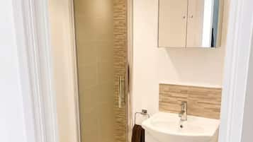 A modern bathroom with a glass shower enclosure, a white sink, and a cabinet above the mirror.