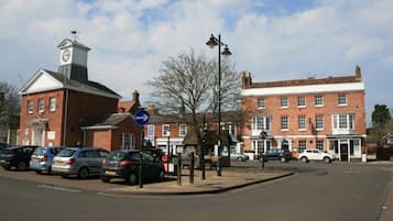 A street with parked cars, a clock tower, and traditional buildings.