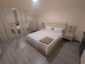 Une chambre à coucher avec un lit, des tables de chevet, une armoire et un miroir.