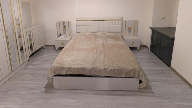 Un dormitorio con cama, mesitas de noche, cómoda y armario.