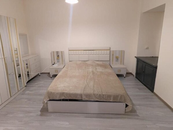 Une chambre à coucher comprenant un lit, des tables de chevet, une commode et une armoire.