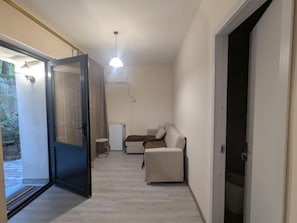 Un couloir étroit avec une porte coulissante donnant sur un balcon, un canapé et une petite table.