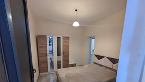 Un dormitorio con cama, armario y espejo.