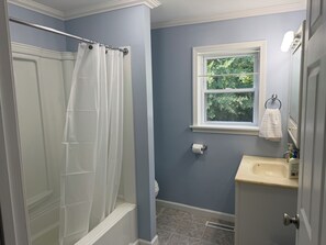 Un bagno con doccia, finestra, lavandino e WC.